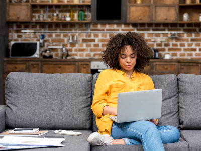 Young woman working working with laptop on couch | Photo: LightField Studios via Shutterstock
